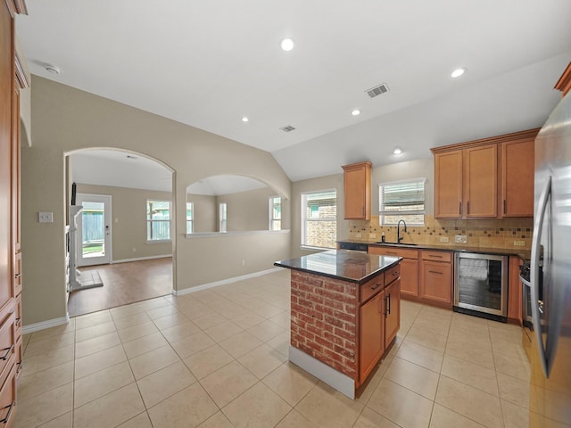 3009 Kurth Canyon Ct, League City, TX 77573 - kitchen with wine cooler, a sink, arched walkways, stainless steel refrigerator, and decorative backsplash