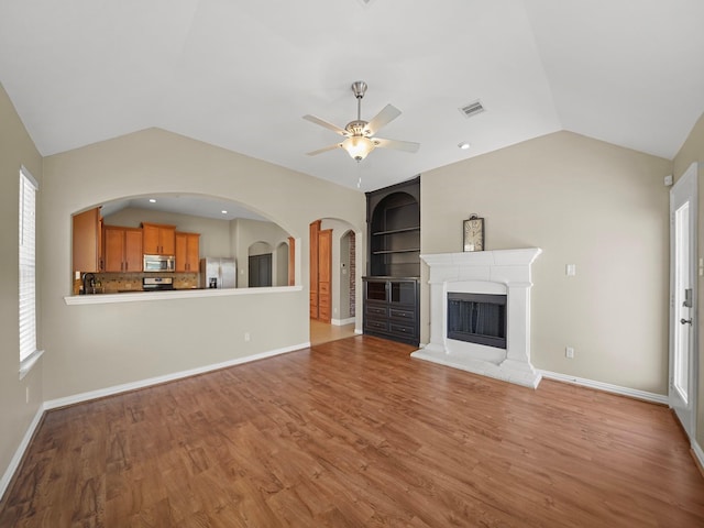 3009 Kurth Canyon Ct, League City, TX 77573 - unfurnished living room with lofted ceiling, a ceiling fan, light wood-style floors, a fireplace with raised hearth, and plenty of natural light