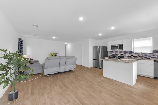 16435 Valerie Marie Pl, Conroe, TX 77306 - kitchen with white cabinets, light wood-style floors, appliances with stainless steel finishes, and a center island