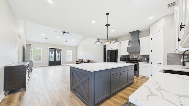 kitchen featuring visible vents, black refrigerator with ice dispenser, electric stove, wall chimney exhaust hood, and a sink