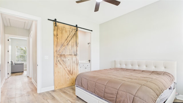 bedroom featuring baseboards, a barn door, light wood finished floors, and attic access