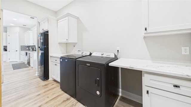 washroom featuring cabinet space, visible vents, light wood finished floors, and washing machine and clothes dryer
