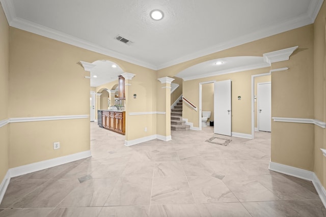 unfurnished room with arched walkways, ornamental molding, and ornate columns