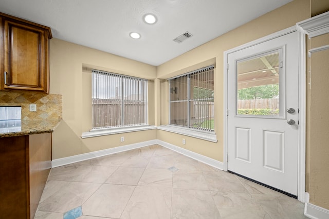 unfurnished dining area with baseboards, a wealth of natural light, and visible vents