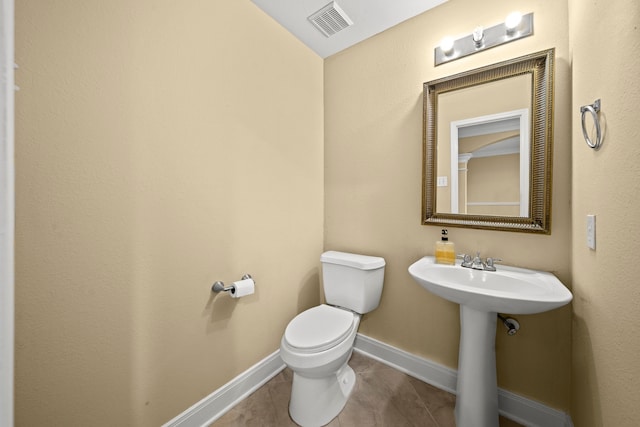 bathroom with visible vents, toilet, baseboards, tile patterned floors, and a sink