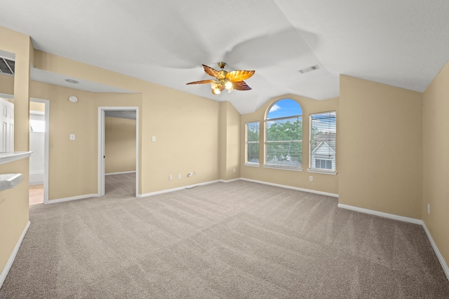 carpeted empty room featuring a ceiling fan, baseboards, visible vents, and lofted ceiling