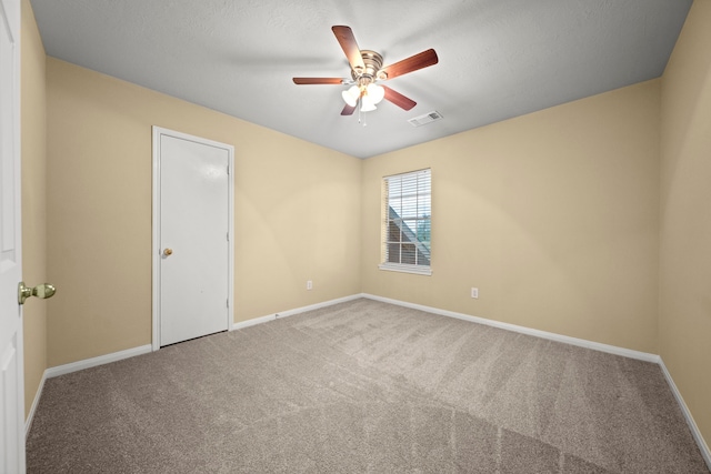 carpeted empty room featuring visible vents, baseboards, and ceiling fan