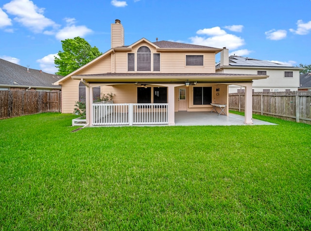 rear view of house with a fenced backyard, ceiling fan, a patio area, and a chimney