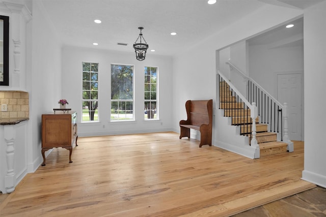 living area with recessed lighting, a notable chandelier, light wood-style flooring, and stairway