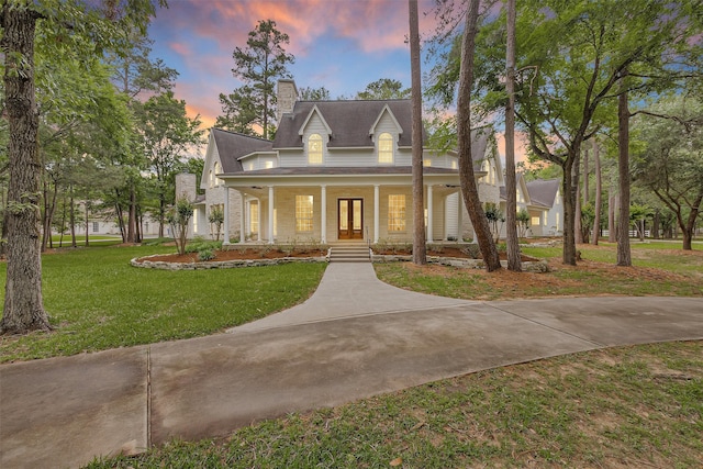view of front of house featuring french doors, a yard, covered porch, and a chimney
