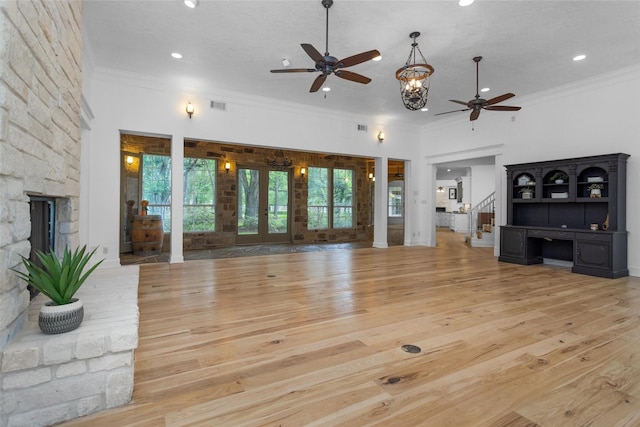 unfurnished living room featuring a ceiling fan, french doors, ornamental molding, and wood finished floors