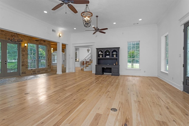 unfurnished living room featuring ornamental molding, ceiling fan with notable chandelier, stairs, and hardwood / wood-style floors