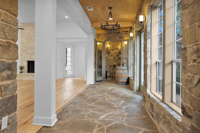 corridor featuring stone flooring, a chandelier, baseboards, visible vents, and wood ceiling