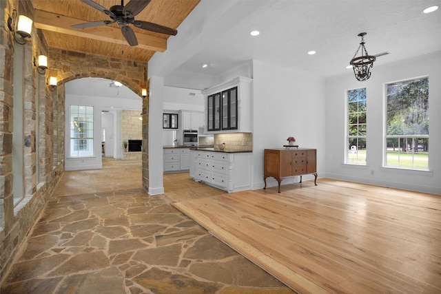 interior space featuring a ceiling fan, recessed lighting, a stone fireplace, and a healthy amount of sunlight