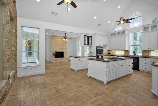 kitchen featuring visible vents, dark countertops, a stone fireplace, ceiling fan, and appliances with stainless steel finishes