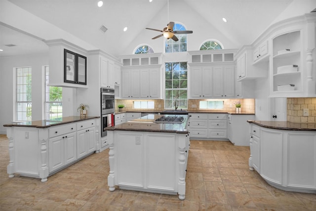 kitchen featuring a peninsula, white cabinetry, ceiling fan, and dark stone counters