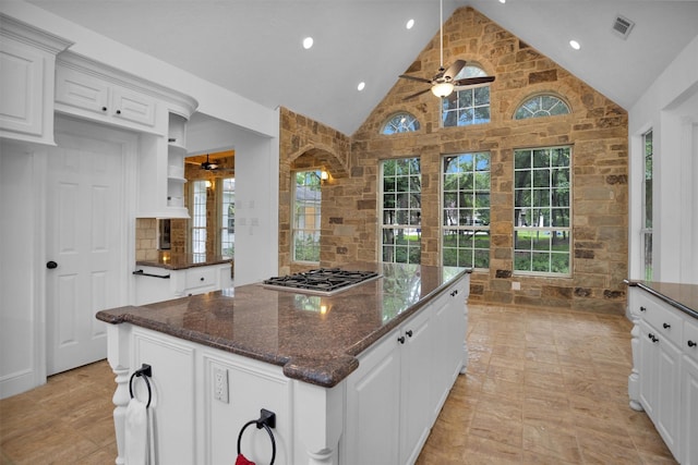 kitchen with stainless steel gas cooktop, a ceiling fan, white cabinetry, a kitchen island, and visible vents