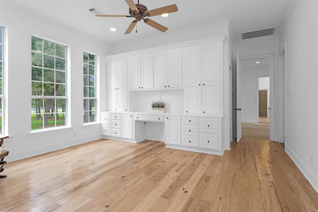 unfurnished office with visible vents, baseboards, built in desk, a ceiling fan, and light wood finished floors