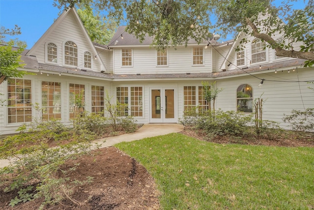 back of house featuring french doors, a lawn, and roof with shingles