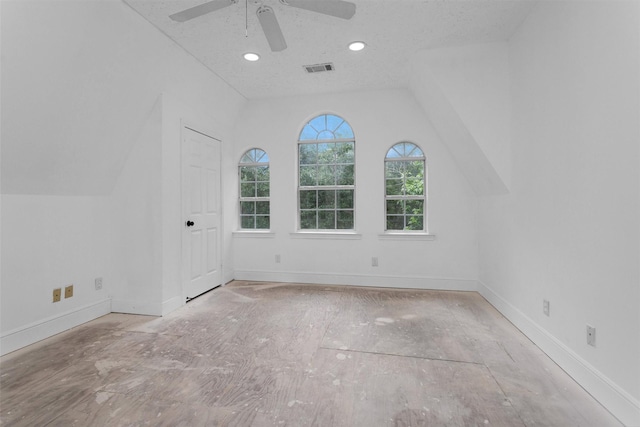 empty room featuring ceiling fan, visible vents, baseboards, and lofted ceiling
