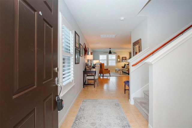foyer entrance featuring a ceiling fan, visible vents, baseboards, stairs, and light tile patterned flooring