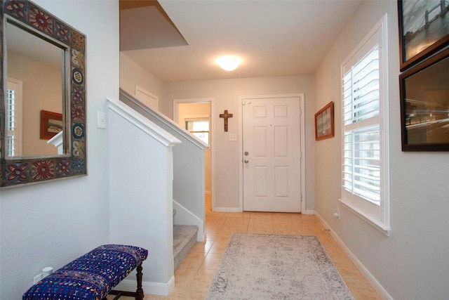 entryway with tile patterned flooring, baseboards, plenty of natural light, and stairway