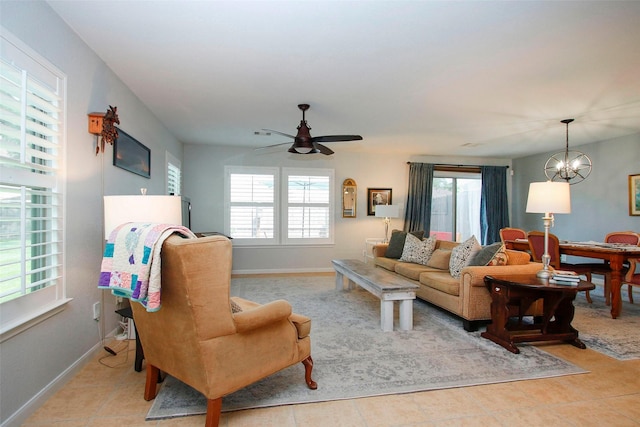 living area with baseboards, light tile patterned floors, and ceiling fan with notable chandelier