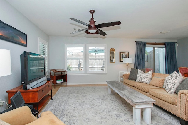 living room with baseboards, ceiling fan, visible vents, and a wealth of natural light