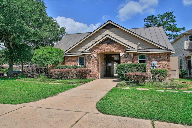 craftsman-style house featuring a standing seam roof, a front yard, metal roof, and stone siding