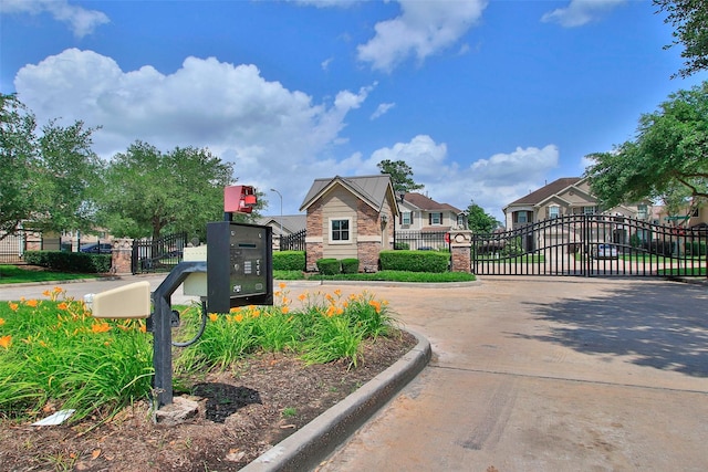 view of street featuring a residential view, a gated entry, a gate, and curbs