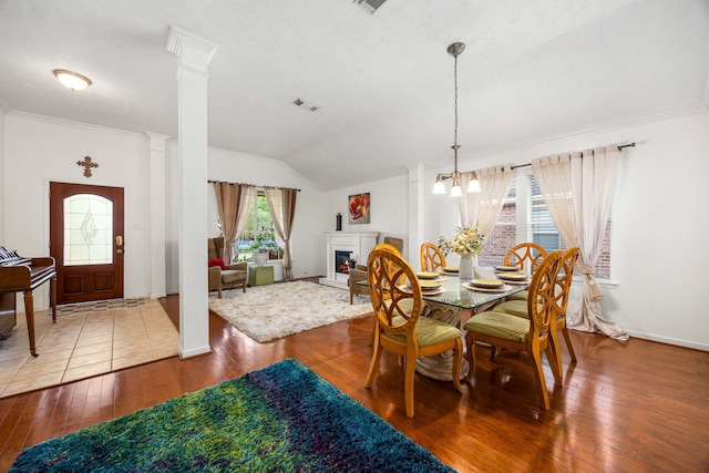 dining room featuring visible vents, crown molding, wood-type flooring, lofted ceiling, and an inviting chandelier