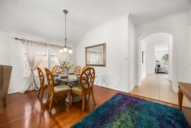 dining room with arched walkways, ornamental molding, wood finished floors, and a chandelier
