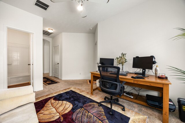 office space with carpet flooring, arched walkways, a ceiling fan, baseboards, and visible vents