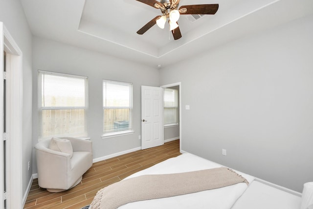 326 Gans St Unit A, Houston, TX 77029 - bedroom featuring baseboards, wood tiled floor, a ceiling fan, and a tray ceiling