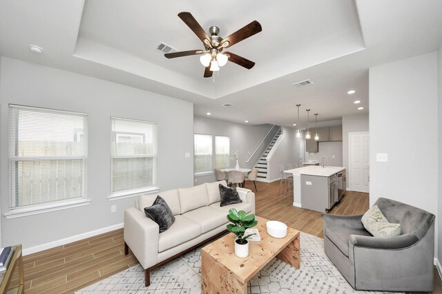 326 Gans St Unit A, Houston, TX 77029 - living area featuring wood tiled floor, visible vents, baseboards, a raised ceiling, and stairs