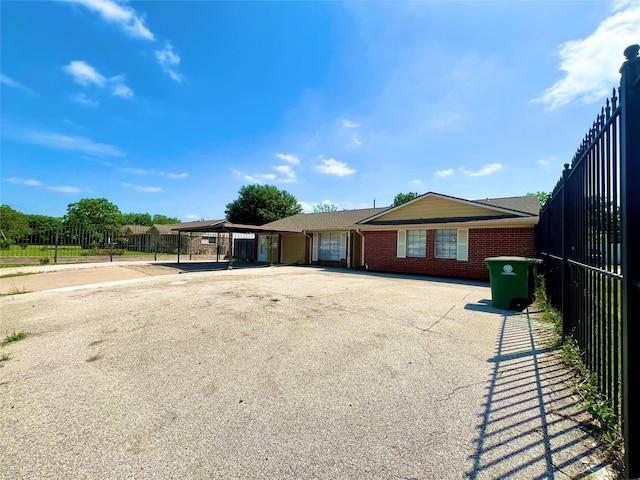 ranch-style home with brick siding, fence, driveway, and a carport