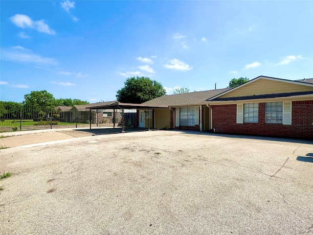 ranch-style home with fence, driveway, and brick siding
