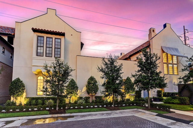 exterior space with a chimney, stucco siding, and a tile roof