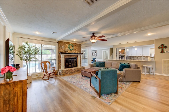 living area featuring crown molding, light wood-style flooring, a textured ceiling, and visible vents