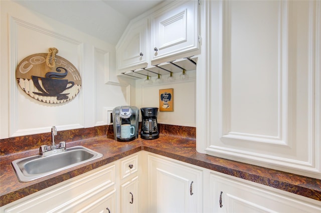 kitchen featuring a sink, dark countertops, and white cabinets
