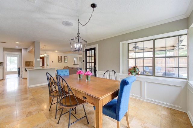 dining room with light tile patterned floors, ornamental molding, a decorative wall, and a notable chandelier