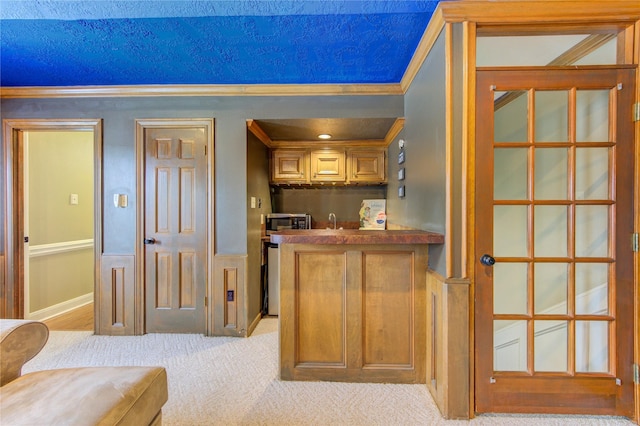 bar featuring crown molding, baseboards, indoor wet bar, stainless steel microwave, and carpet flooring