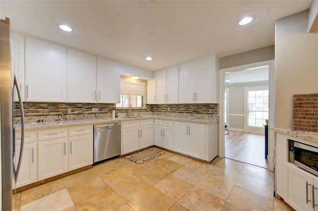 kitchen featuring stainless steel appliances, decorative backsplash, a healthy amount of sunlight, and white cabinetry