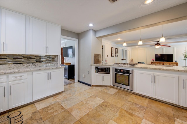 kitchen with stone finish floor, decorative backsplash, stainless steel appliances, and white cabinets