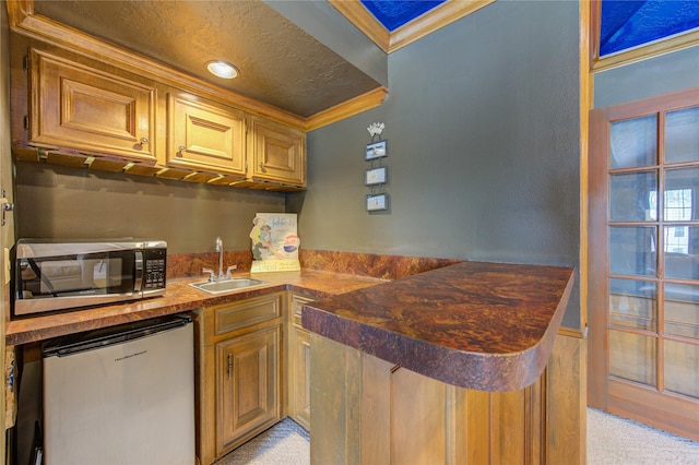 bar with wet bar, refrigerator, a sink, stainless steel microwave, and ornamental molding