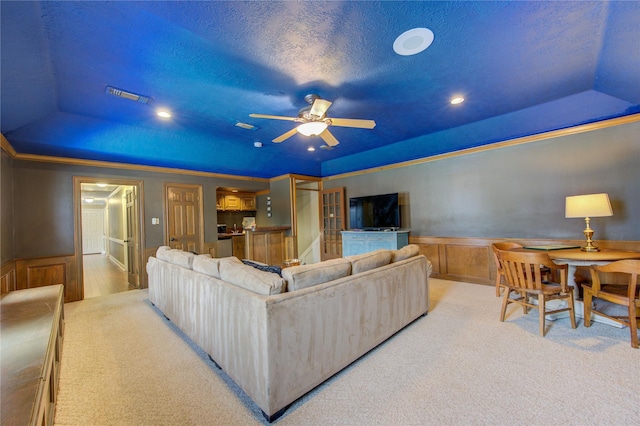 living area featuring a ceiling fan, visible vents, wainscoting, and carpet