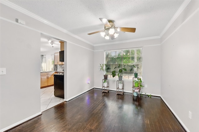 empty room featuring crown molding, wood finished floors, baseboards, ceiling fan, and a textured ceiling