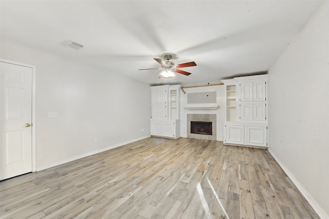 unfurnished living room with ceiling fan, visible vents, a fireplace, baseboards, and light wood finished floors