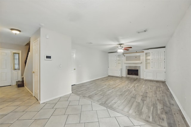 unfurnished living room featuring ceiling fan, visible vents, baseboards, and a fireplace