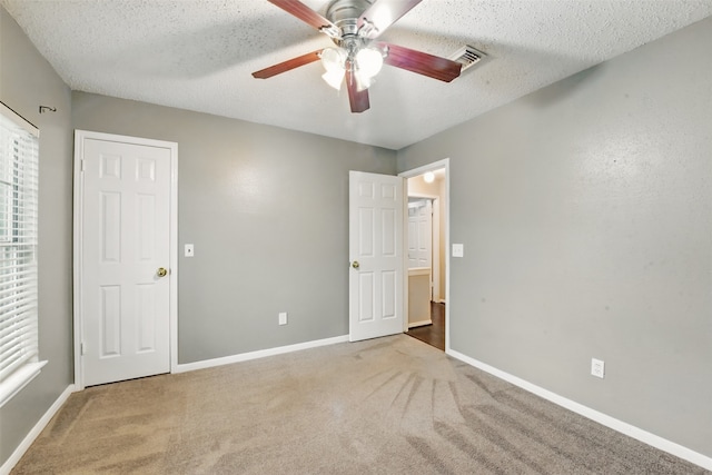 unfurnished bedroom with carpet floors, baseboards, a textured ceiling, and visible vents